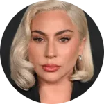 A person with styled blonde hair and elegant earrings faces forward. The backdrop is dark, emphasizing the person's features.